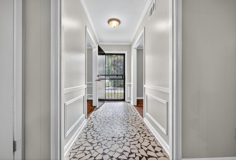 Doorway to outside with crown molding and a decorative wall