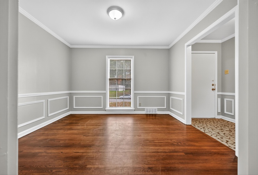 Unfurnished room with crown molding, dark wood-style floors, and a decorative wall