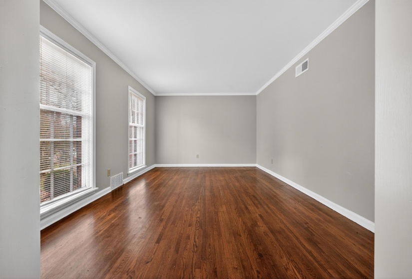 Empty room featuring ornamental molding and dark wood-style flooring