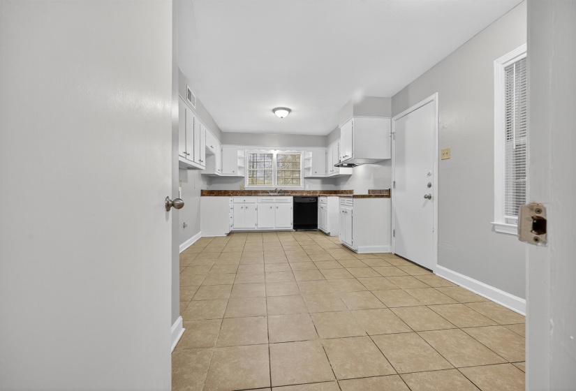 Kitchen with white cabinets, light tile patterned flooring, open shelves, and black dishwasher