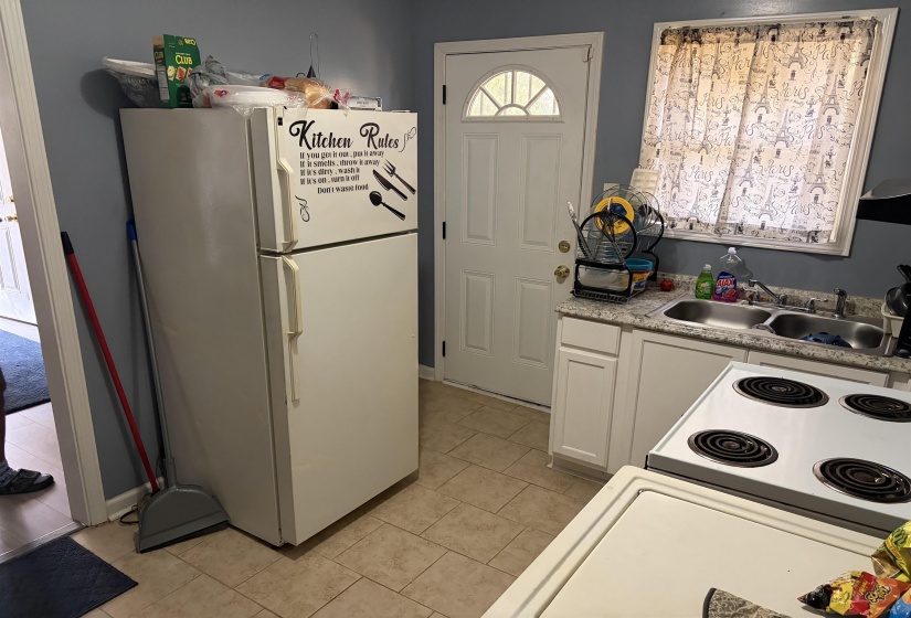 Kitchen featuring white appliances, light countertops, white cabinets, and light tile patterned floors