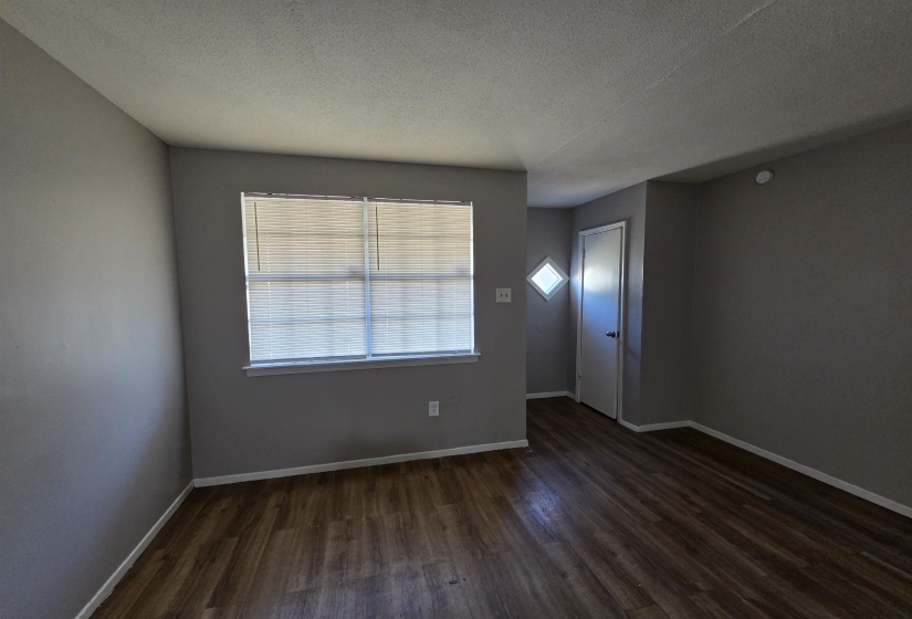 Unfurnished room featuring dark wood-style flooring and a textured ceiling