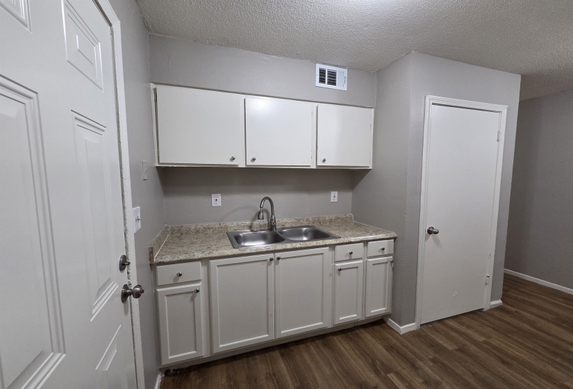 Kitchen with dark wood-type flooring, light countertops, white cabinetry, and a textured ceiling