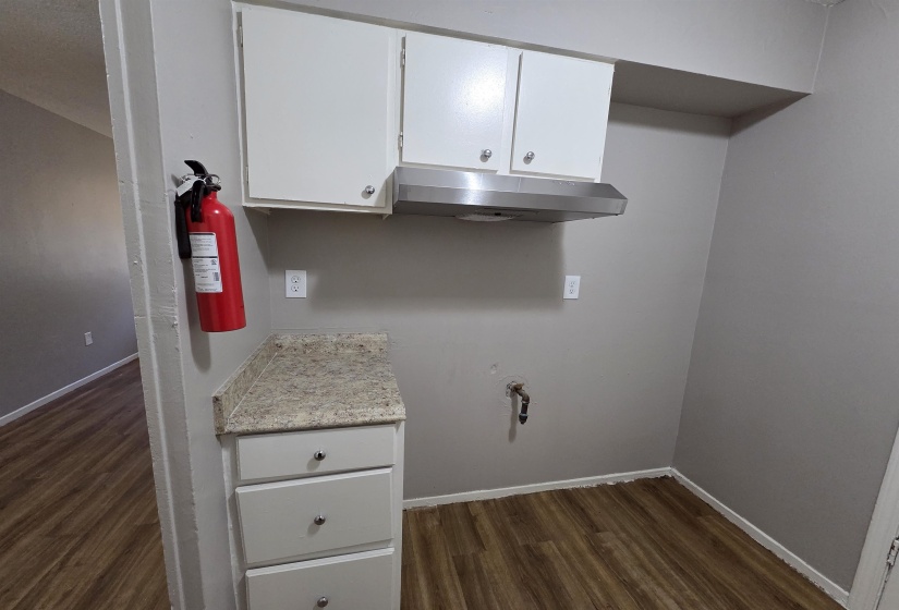 Kitchen with white cabinetry, dark wood-style flooring, and under cabinet range hood
