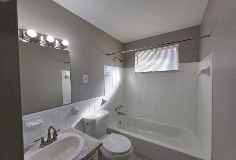 Bathroom featuring bathing tub / shower combination, vanity, and tile walls