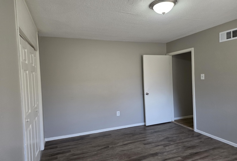 Unfurnished bedroom featuring dark wood finished floors, a textured ceiling, and a closet