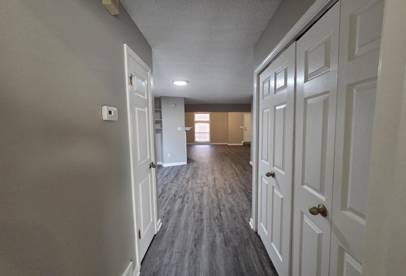 Hallway with a textured ceiling and dark wood-type flooring