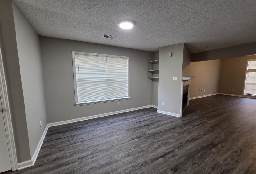 Unfurnished living room featuring dark wood-style floors, a fireplace with flush hearth, and a textured ceiling