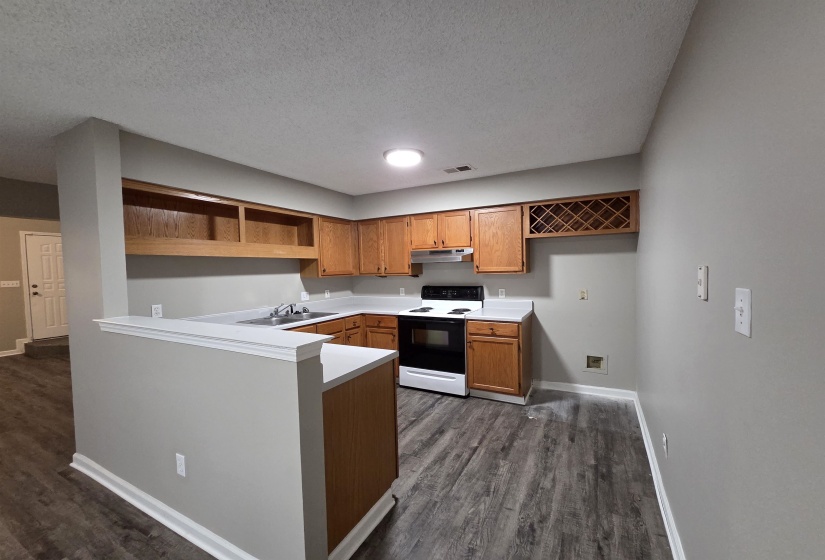 Kitchen featuring open shelves, light countertops, electric range oven, brown cabinets, and dark wood-style flooring