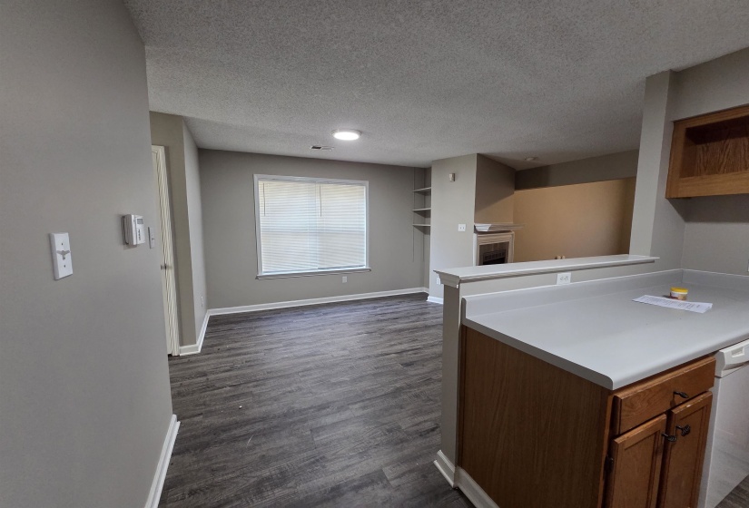Kitchen featuring light countertops, a textured ceiling, dark wood finished floors, open shelves, and white dishwasher