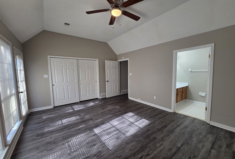 Unfurnished bedroom featuring vaulted ceiling, dark wood-type flooring, ceiling fan, a closet, and connected bathroom