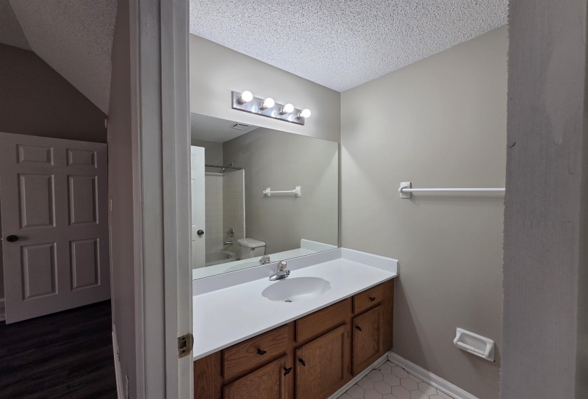 Bathroom with vanity,  shower combination, a textured ceiling, and light tile patterned floors