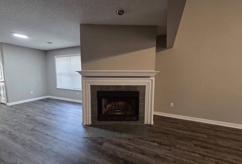 Unfurnished living room featuring a textured ceiling, a fireplace, and dark wood-type flooring