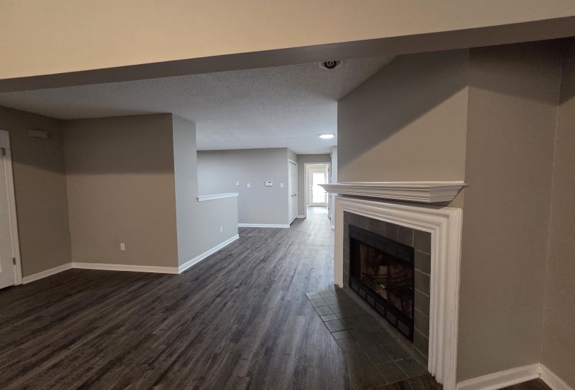 Unfurnished living room with dark wood finished floors, a tile fireplace, and a textured ceiling