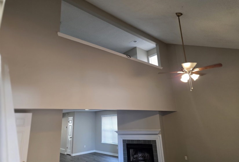 Unfurnished living room with a tile fireplace, high vaulted ceiling, dark wood-style floors, and a ceiling fan