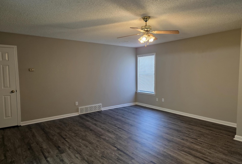 Empty room featuring dark wood-style floors, a textured ceiling, and ceiling fan