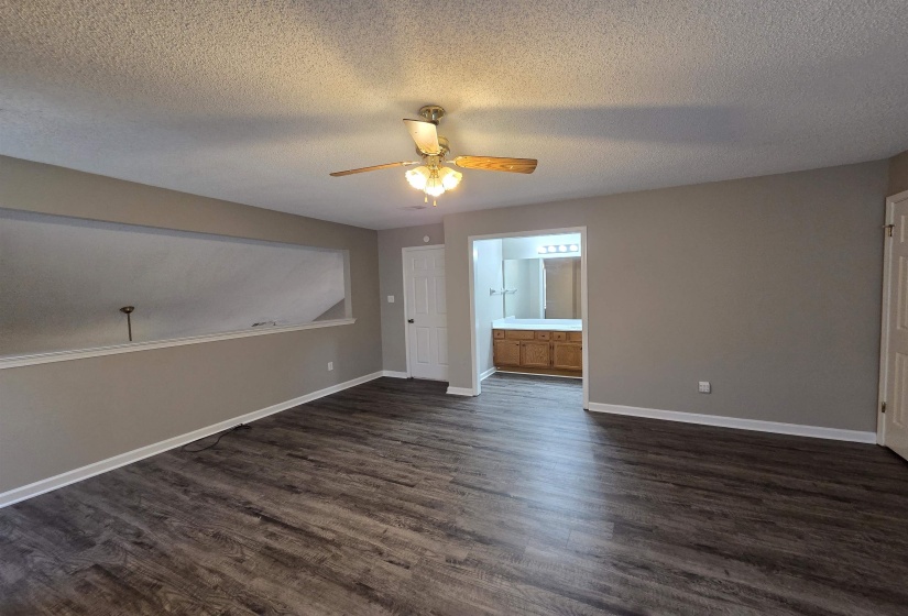 Spare room featuring a textured ceiling, dark wood-style floors, and a ceiling fan