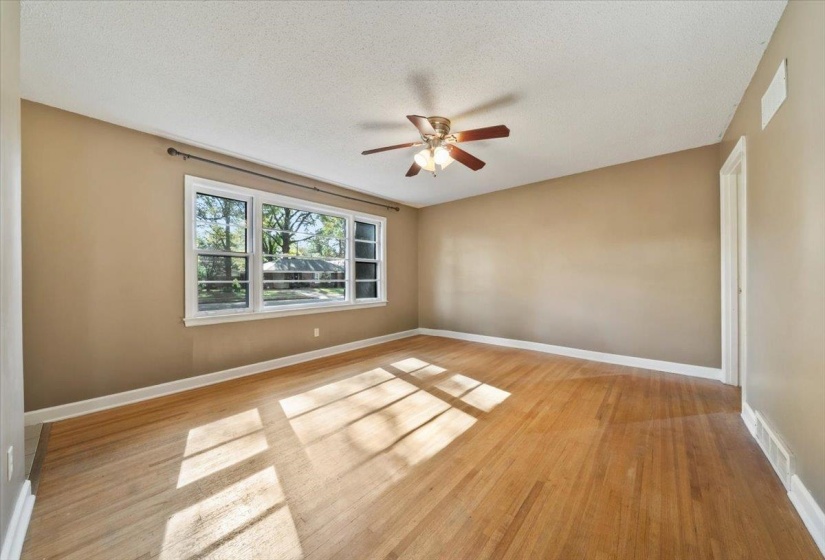 Empty room with a textured ceiling, light wood finished floors, and ceiling fan