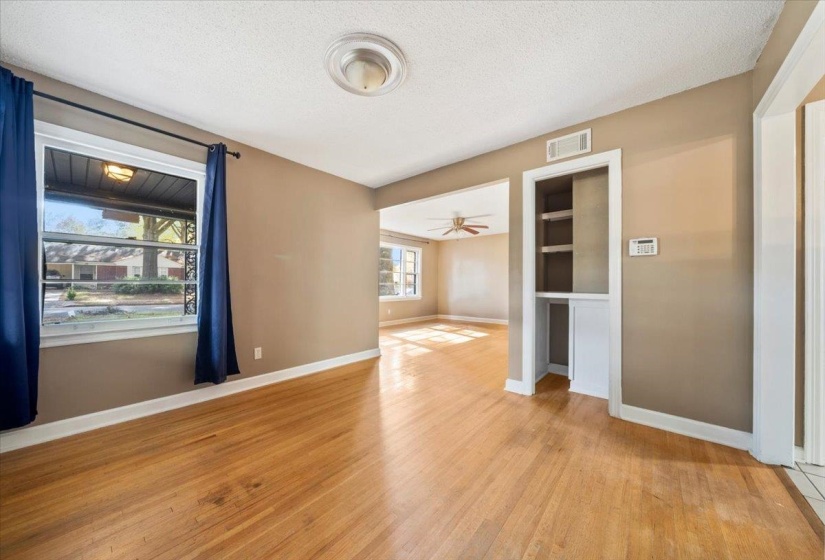 Spare room featuring a textured ceiling, light wood-type flooring, built in features, and a ceiling fan