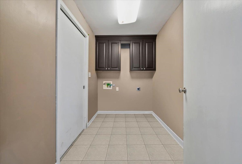 Laundry room with light tile patterned flooring, hookup for an electric dryer, cabinet space, and hookup for a washing machine