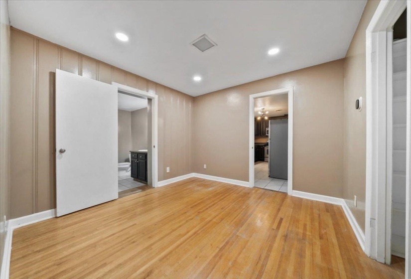 Unfurnished bedroom featuring connected bathroom, light wood finished floors, recessed lighting, and freestanding refrigerator