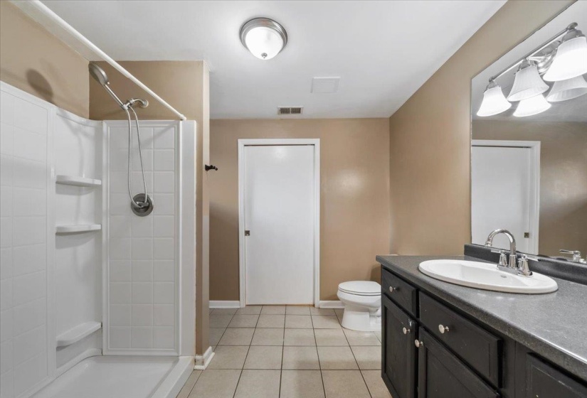 Full bathroom featuring light tile patterned floors, vanity, and a shower stall