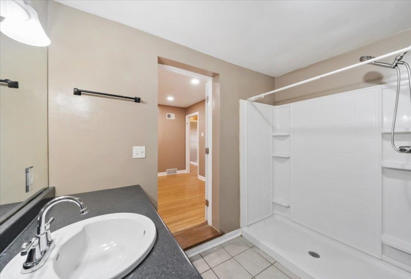 Full bath featuring light tile patterned floors, a stall shower, and vanity