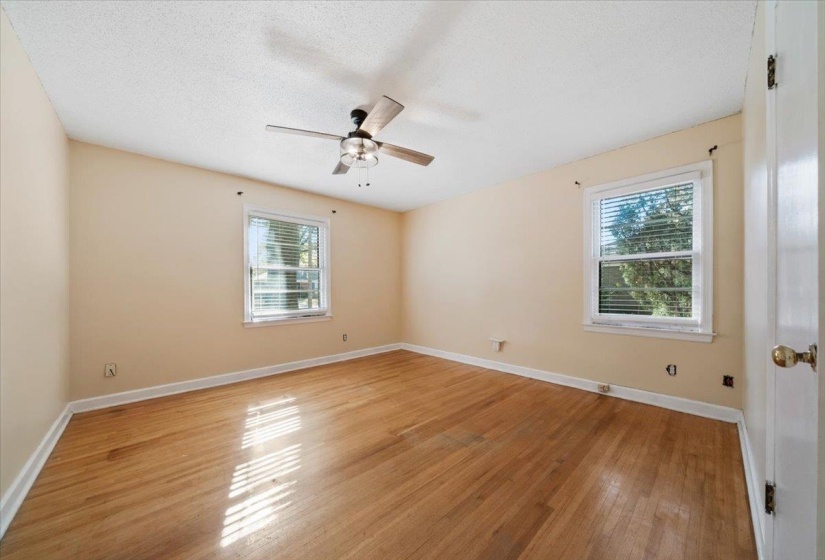 Spare room featuring light wood finished floors, plenty of natural light, a textured ceiling, and a ceiling fan