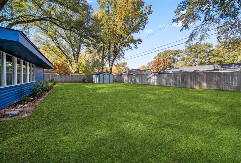 Fenced backyard featuring a storage shed and a sunroom