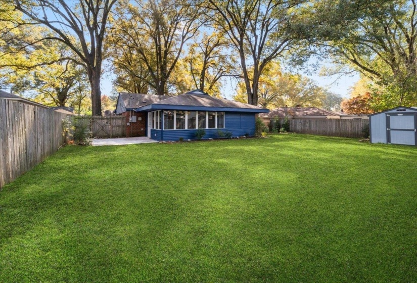 Back of house with a sunroom, a fenced backyard, a patio, and a storage unit