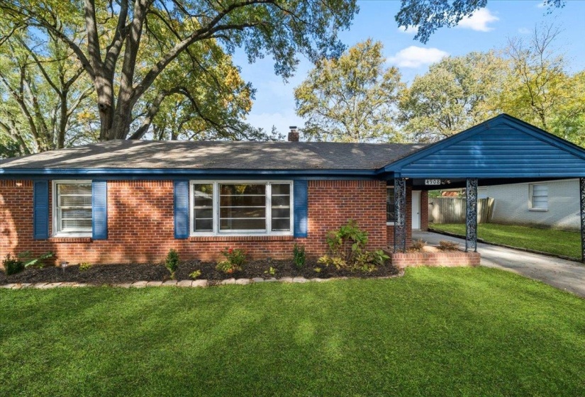 Ranch-style home featuring a front lawn, an attached carport, brick siding, a chimney, and concrete driveway