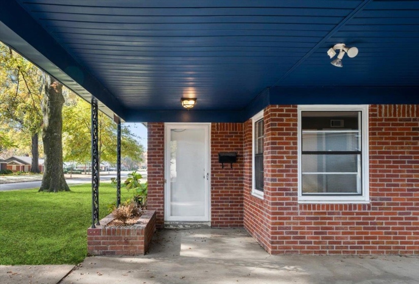 Property entrance featuring brick siding, a porch, and a lawn