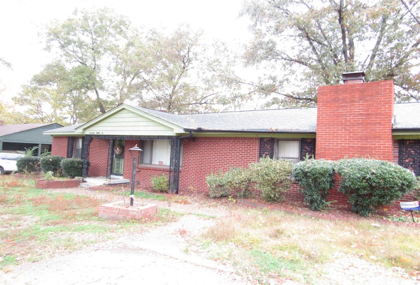 View of front of property with a chimney, brick siding, and covered porch