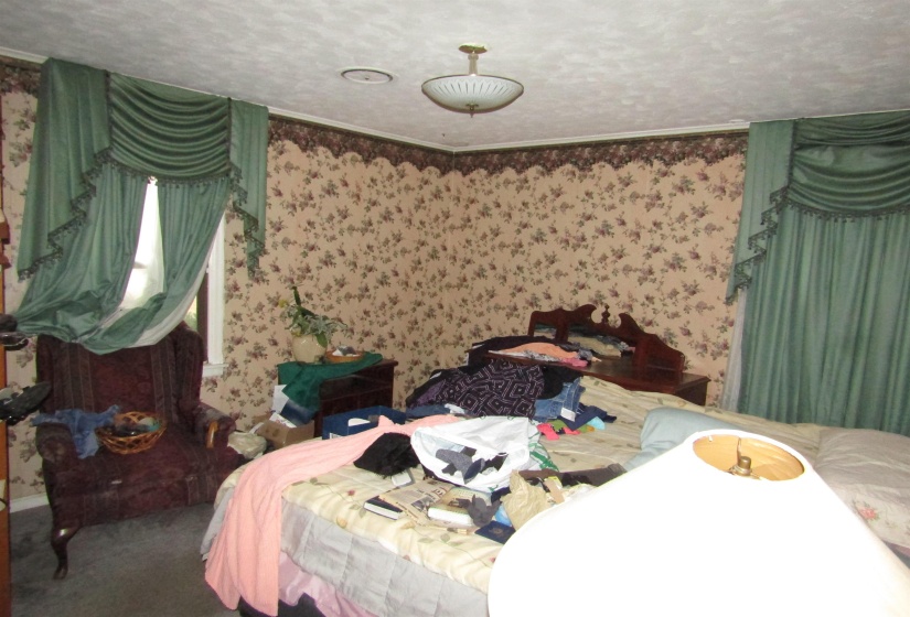 Bedroom featuring carpet flooring, a textured ceiling, and wallpapered walls