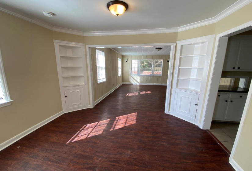 Unfurnished dining area with built in shelves, dark wood finished floors, and ornamental molding