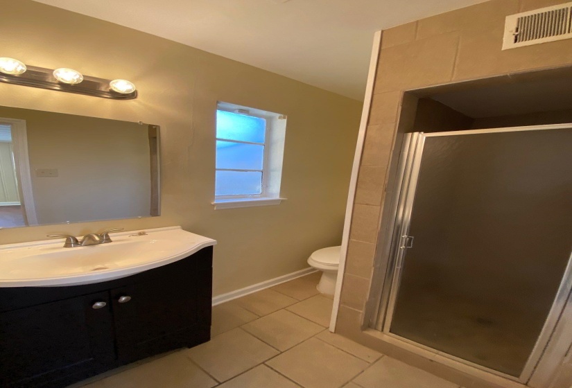 Full bath with light tile patterned floors, vanity, and a shower stall