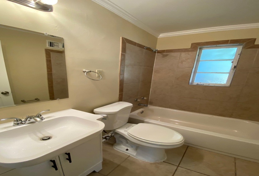 Bathroom featuring bathtub / shower combination, vanity, tile patterned flooring, and crown molding