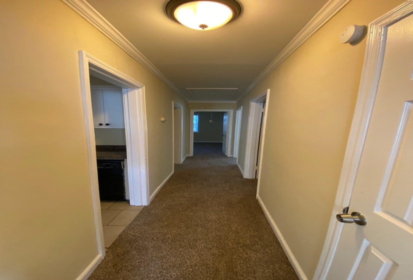 Hall with light colored carpet, ornamental molding, attic access, and light tile patterned floors