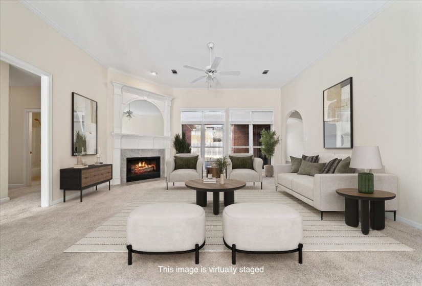 Living room with ornamental molding, light colored carpet, a lit fireplace, and a ceiling fan