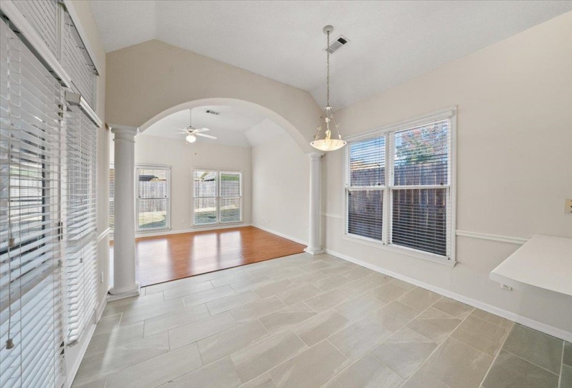 Unfurnished dining area featuring arched walkways, decorative columns, lofted ceiling, and a ceiling fan