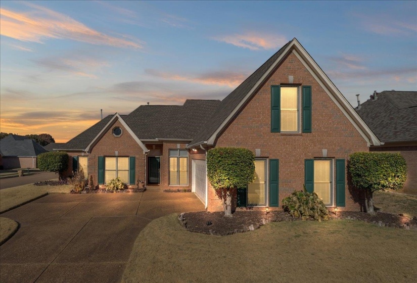 View of front of property with brick siding, concrete driveway, an attached garage, and a lawn