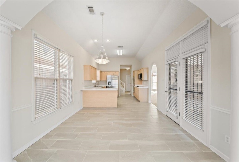 Kitchen with decorative columns, arched walkways, light brown cabinets, light countertops, and recessed lighting