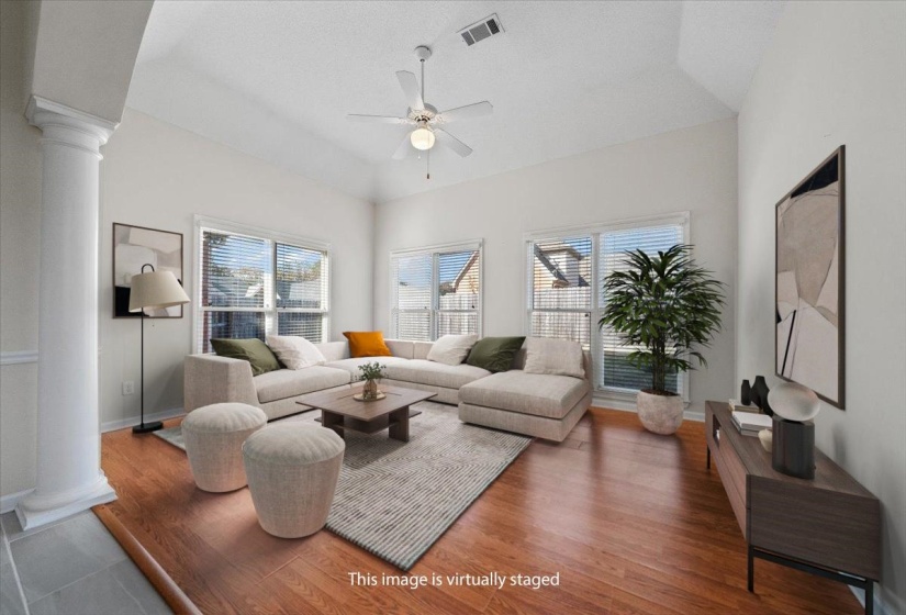 Living room featuring ornate columns, wood finished floors, vaulted ceiling, and ceiling fan