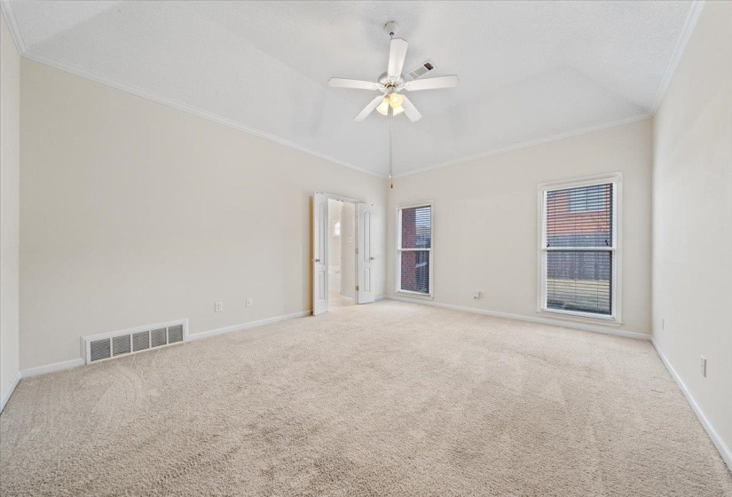 Carpeted empty room featuring ornamental molding, a ceiling fan, and vaulted ceiling