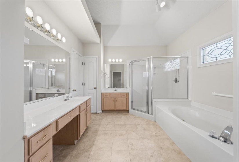 Full bathroom with two vanities, a bath, a stall shower, and light tile patterned floors