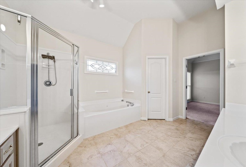 Full bath with vanity, a bath, a stall shower, lofted ceiling, and light tile patterned floors