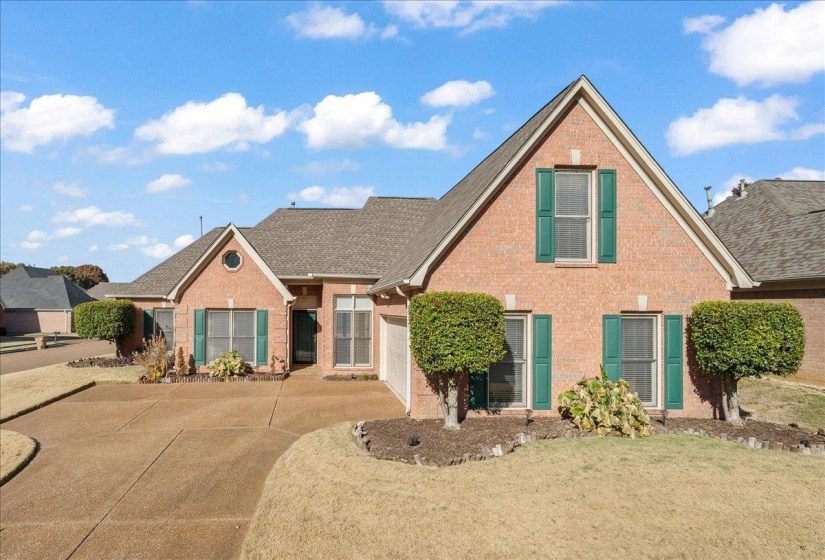 Traditional-style house featuring brick siding, a shingled roof, concrete driveway, and a front yard