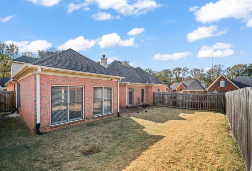 Back of house featuring brick siding, a fenced backyard, a shingled roof, and a chimney