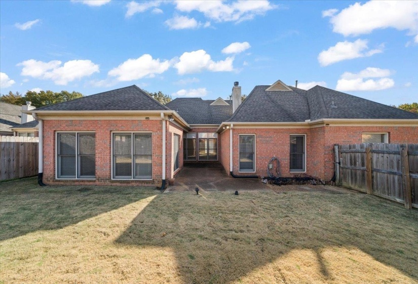 Rear view of property featuring a fenced backyard, roof with shingles, brick siding, and a chimney