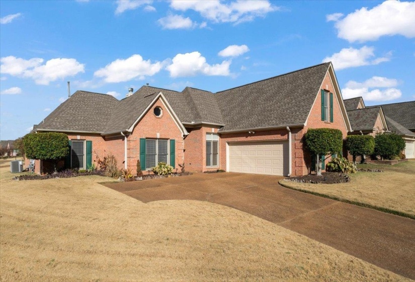 View of front of property with roof with shingles, concrete driveway, brick siding, and a front yard